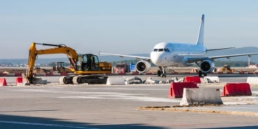 excavator on airfield with plane