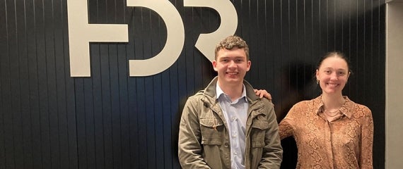 2 HDR interns in office in front of HDR signage