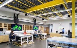 lab with students and instructor, tv screens with generic green organisms