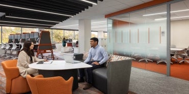 Office space interior with workers sat at desk.