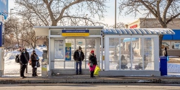 people waiting at bus stop with snow on ground