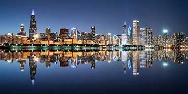 Nighttime skyline of Chicago. Skyscrapers show in the background. River shown in foreground., 