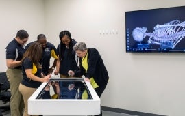 students and an instructor looking down at a digital screen