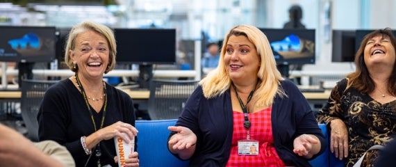 Three women speaking with enthusiasm sharing laughter and smiles.