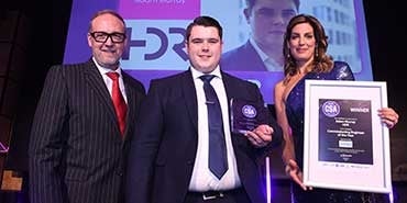 Three people on stage with an award presented.