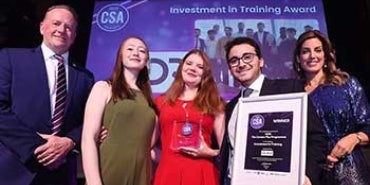 Four people posing on stage with an award certificate. 