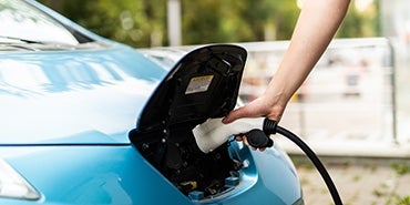 person putting charger in electric vehicle