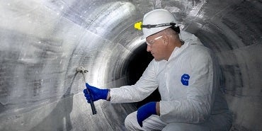 Man inspecting the inside of a pipeline