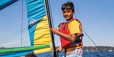 A boy learns to sail on a Sail Sand Point excursion 