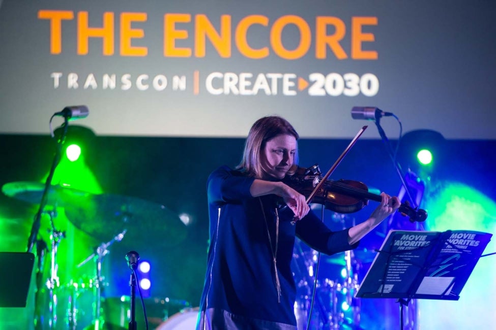 woman playing violin on stage at HDR transportation internal conference talent show