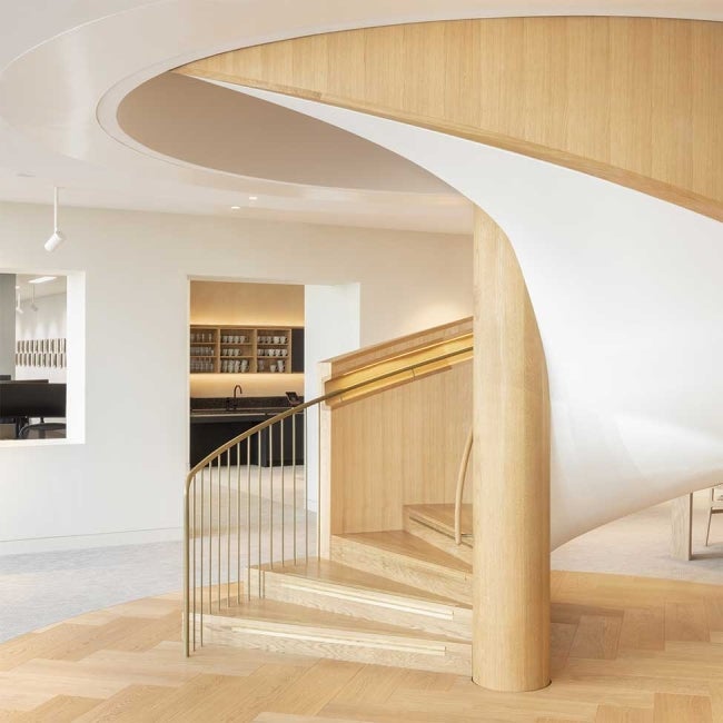 Interior of 22 Bishopsgate, London. Next to the bottom of a flight of stairs. A kitchen area can be seen at the baclk.