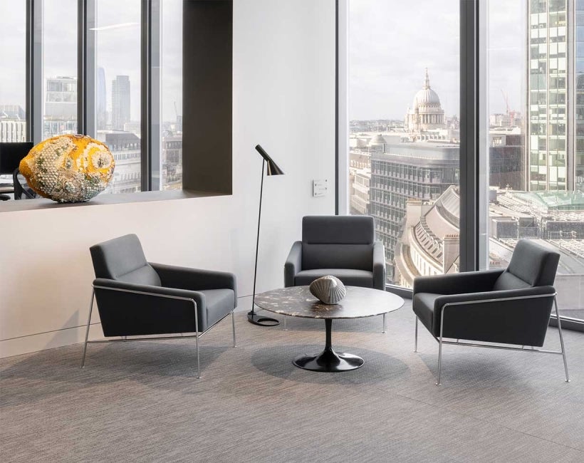 Office room with a small round table and 3 chairs placed around it. St Paul's Cathedral and buildings in London can be seen in the background.,