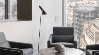 Interior of office at 22 Bishopsgate, London. Chairs placed around a desk with a view of London out of window.