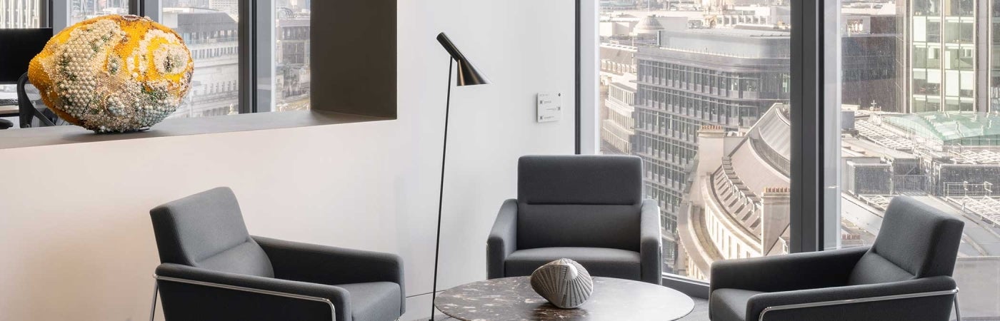 Interior of office at 22 Bishopsgate, London. Chairs placed around a desk with a view of London out of window.