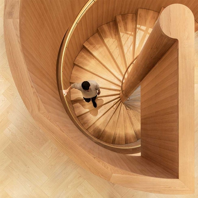 Interior overhead picture of man descending on wooden spiral staircase.