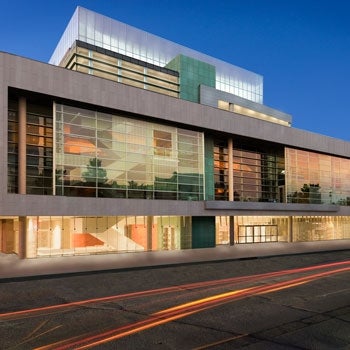 Exterior view of the Omaha Performing Arts Center at night, with street lights shining in the foreground