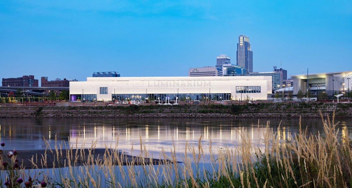 exterior view of Kiewit Luminarium from opposite river bank at dusk