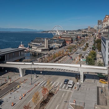 Aerial photo of the Marion Street Pedestrian Bridge in downtown Seattle with the ocean in the background.