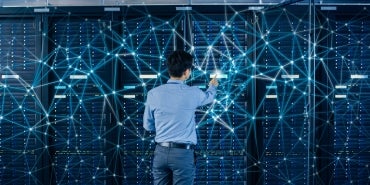 Internet Web Concept. Shot In the Modern Data Center: IT Engineer Standing Beside Open Server Rack Cabinets and Touching Digital Connections on a Server.