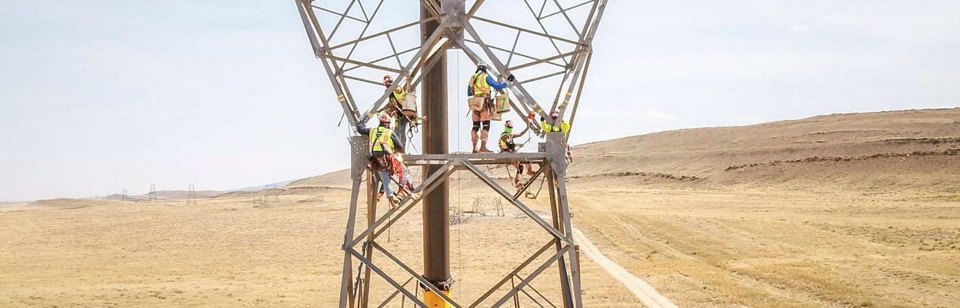 Linemen assemble a 500kV steel lattice tower with the aid of a crane