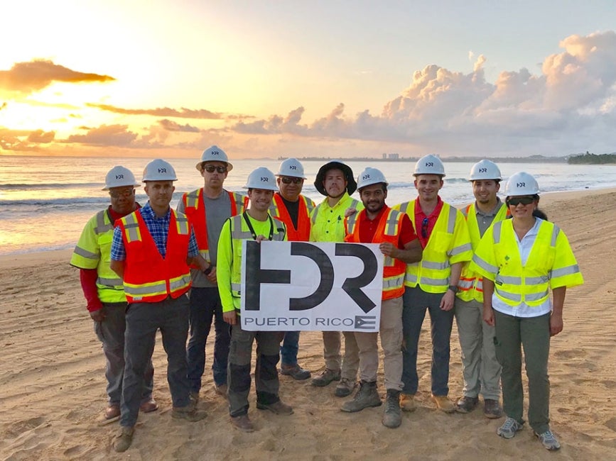 employees with sign on beach in Puerto Rico