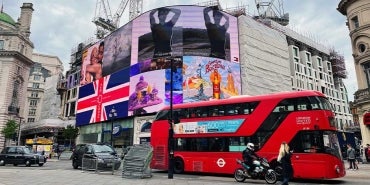 The large advertising display at Piccadilly Circus, London, UK, with an iconic red London bus in front.