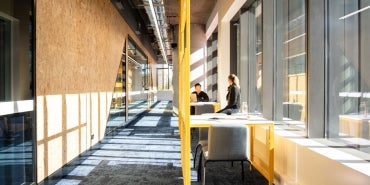 Two students conversing at a table in a daylight filled corridor at Western Sydney University Bankstown City Campus