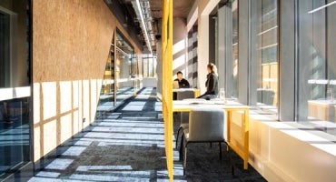 Two students conversing at a table in a daylight filled corridor at Western Sydney University Bankstown City Campus