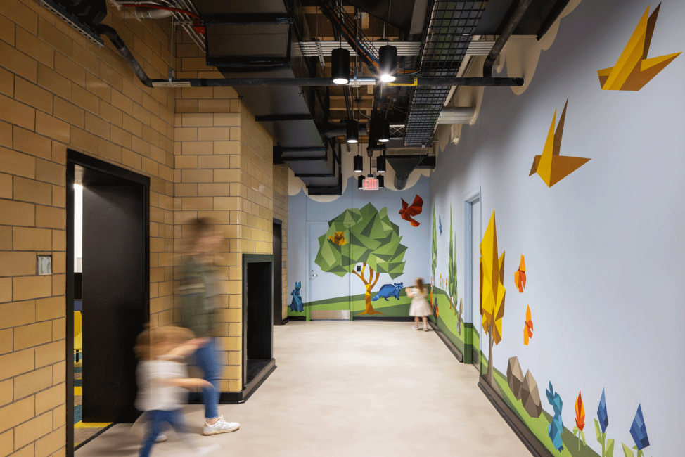 A photo of the colorful mural with trees and origami birds leading the way to the children's area at the Omaha Public Library Downtown Branch