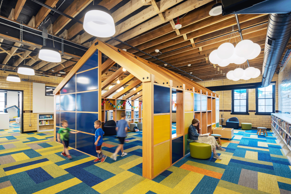 A photo of children playing in the Story House structure at the Omaha Public Library Downtown Branch